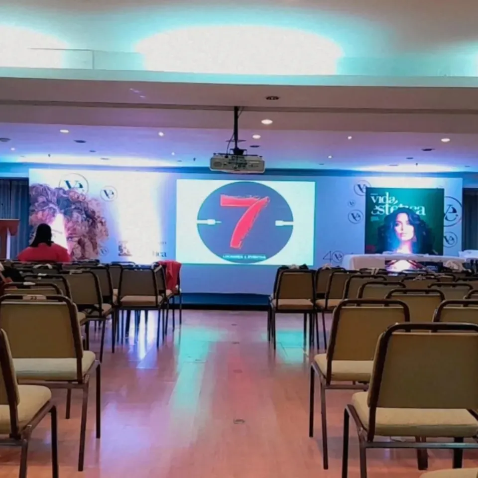 Auditório organizado com cadeiras, projeção, palco e iluminação