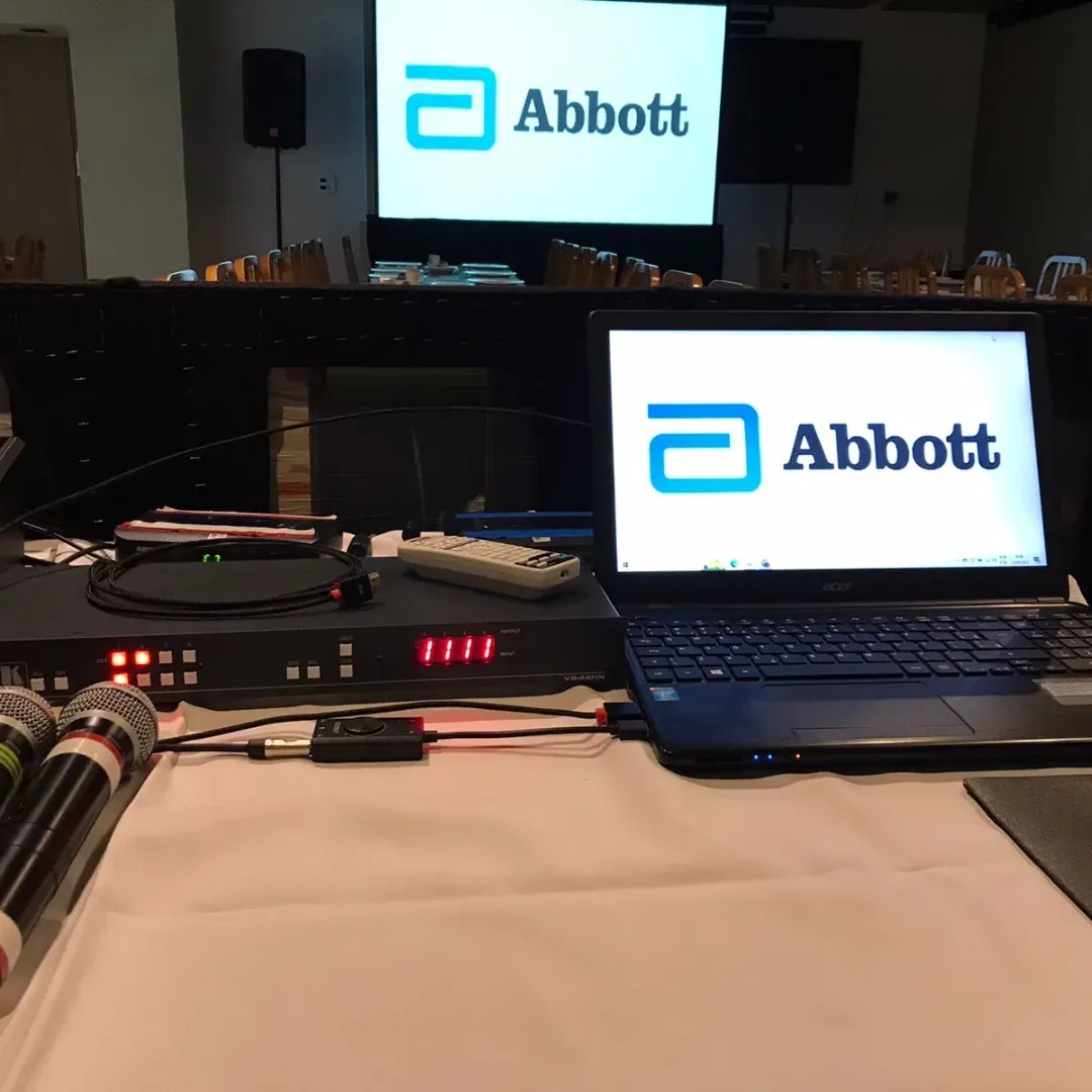 Computador, microfones e controles audiovisuais nos bastidores de um evento